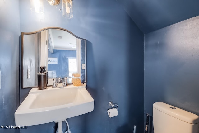 bathroom with a sink, toilet, and visible vents