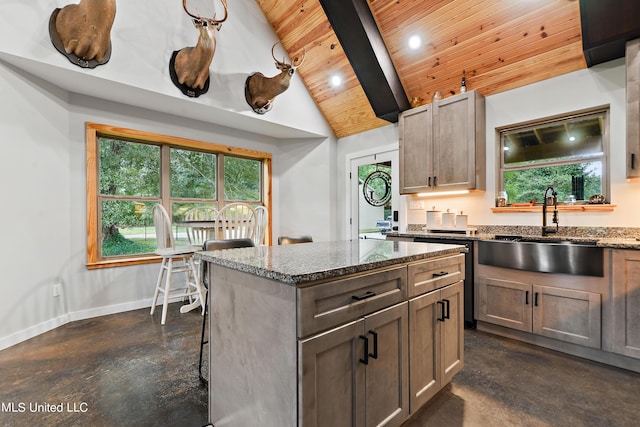 kitchen with lofted ceiling with beams, a sink, concrete flooring, dark stone counters, and baseboards