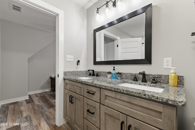 bathroom with double vanity, visible vents, a sink, and wood finished floors