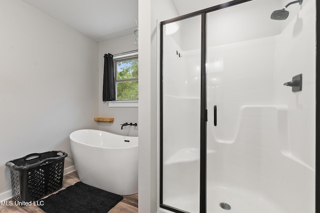 full bath with a stall shower, a freestanding bath, and wood finished floors