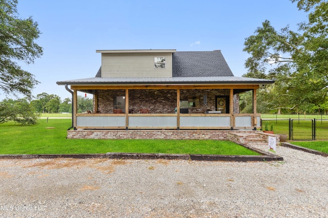 back of property with metal roof, a porch, brick siding, fence, and a lawn