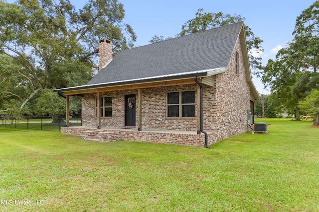 view of front of property with a front lawn, a chimney, brick siding, and central air condition unit