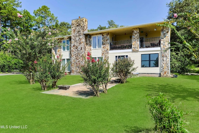 rear view of property featuring a balcony and a yard