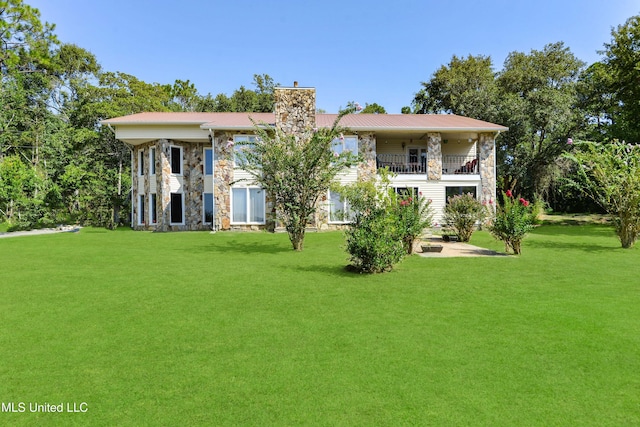 back of house with a lawn and a balcony