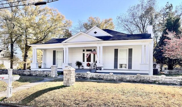 view of front of house featuring covered porch, a front yard, and fence