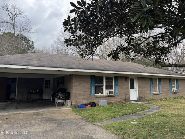 ranch-style home with concrete driveway, an attached carport, cooling unit, a front lawn, and brick siding