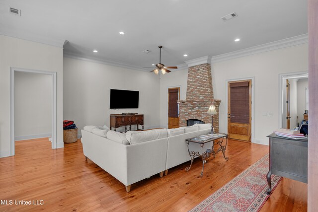 living room with light hardwood / wood-style floors, crown molding, a fireplace, and ceiling fan