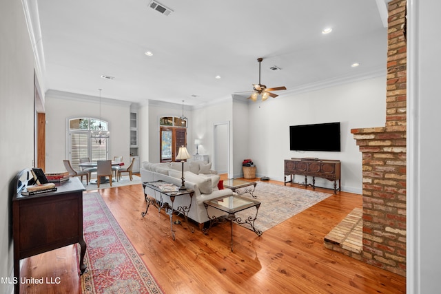 living room with light hardwood / wood-style floors, crown molding, and ceiling fan with notable chandelier