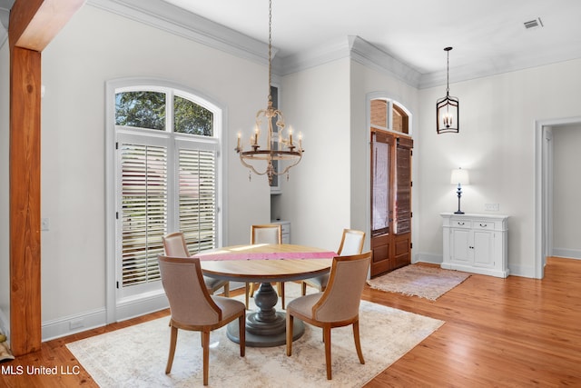 dining room with a notable chandelier, light hardwood / wood-style floors, and crown molding