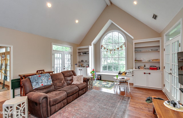 living room featuring light hardwood / wood-style flooring, french doors, beam ceiling, and high vaulted ceiling