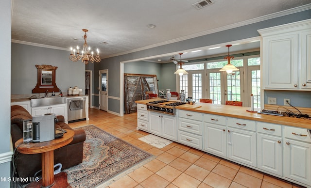 kitchen with appliances with stainless steel finishes, white cabinetry, butcher block counters, and hanging light fixtures