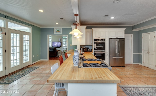 kitchen with ornamental molding, white cabinets, stainless steel appliances, and pendant lighting