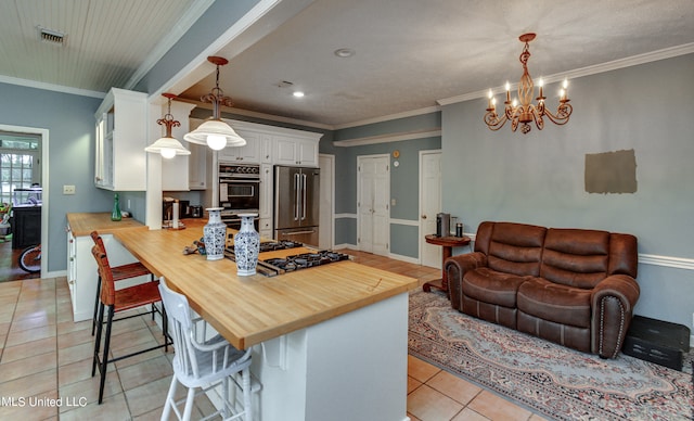 kitchen featuring a kitchen breakfast bar, wood counters, white cabinetry, stainless steel appliances, and decorative light fixtures