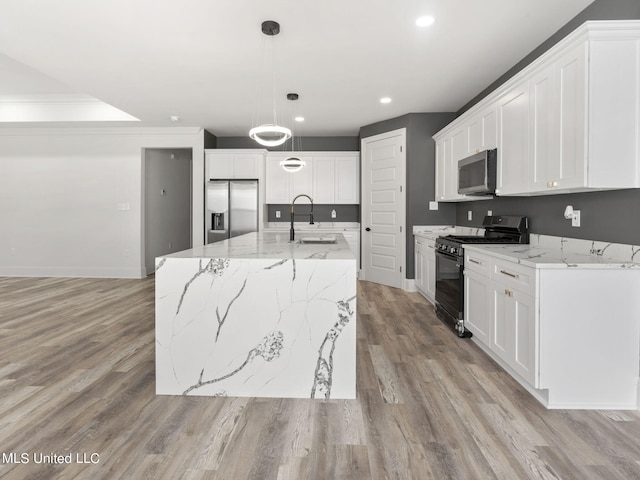 kitchen featuring an island with sink, sink, white cabinetry, light wood-type flooring, and appliances with stainless steel finishes