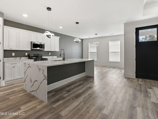 kitchen featuring white cabinets, stainless steel appliances, hanging light fixtures, and a kitchen island with sink