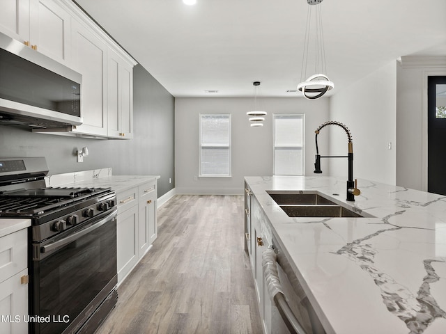 kitchen with appliances with stainless steel finishes, sink, light hardwood / wood-style floors, decorative light fixtures, and white cabinets