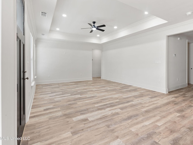 empty room featuring light hardwood / wood-style flooring, ornamental molding, a tray ceiling, and ceiling fan