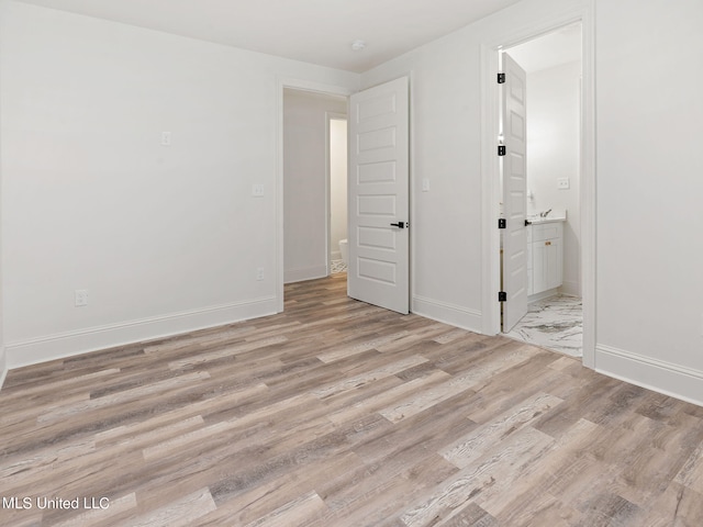 unfurnished bedroom featuring ensuite bath and light wood-type flooring