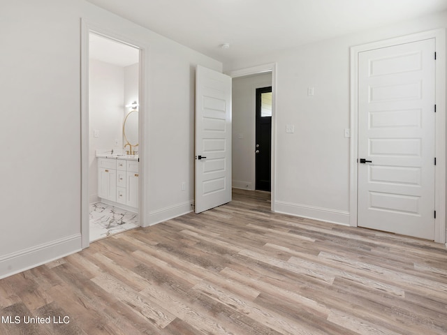 unfurnished bedroom with a closet, ensuite bathroom, and light hardwood / wood-style floors