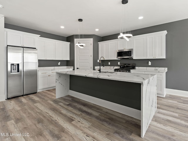 kitchen with appliances with stainless steel finishes, white cabinetry, sink, and hanging light fixtures