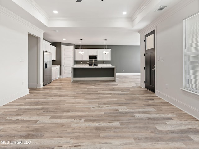 kitchen with white cabinets, a kitchen island with sink, light hardwood / wood-style flooring, pendant lighting, and stainless steel appliances