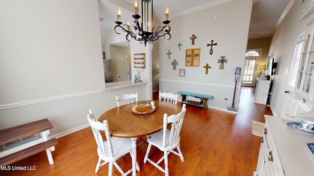 dining room with baseboards, wood finished floors, a notable chandelier, and ornamental molding