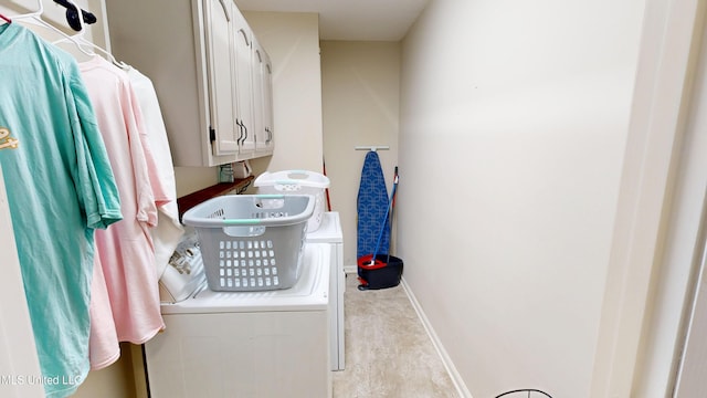 clothes washing area with washer and dryer, cabinet space, and baseboards