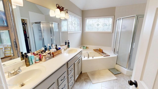 bathroom with double vanity, a stall shower, a garden tub, and a sink