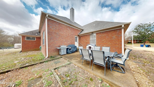 back of property featuring brick siding, outdoor dining space, a chimney, and a patio area