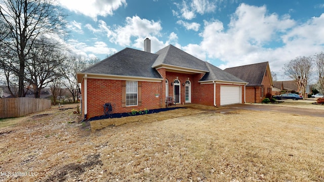 view of front of property with brick siding, a front lawn, fence, driveway, and an attached garage