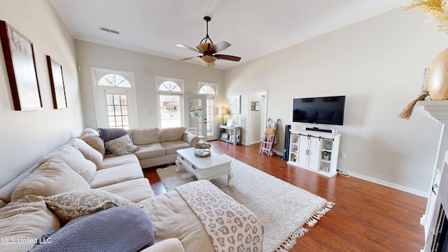 living area with a ceiling fan, visible vents, baseboards, dark wood-type flooring, and crown molding