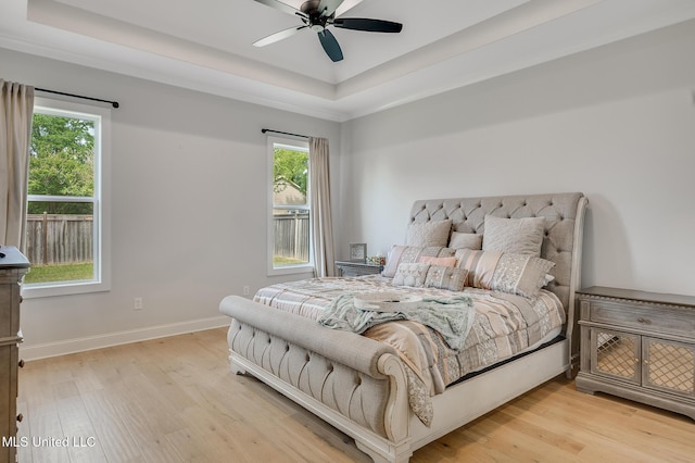 101 Coventry Ln, Canton, MS 39046 - bedroom with light wood-type flooring, a tray ceiling, and multiple windows