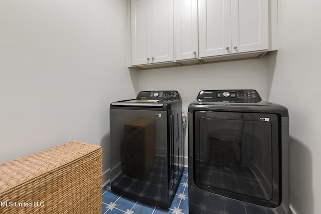 laundry room with washer and clothes dryer, dark tile patterned flooring, and cabinets