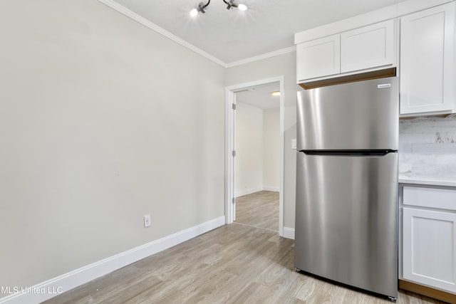 kitchen featuring white cabinets, light hardwood / wood-style flooring, crown molding, and stainless steel refrigerator