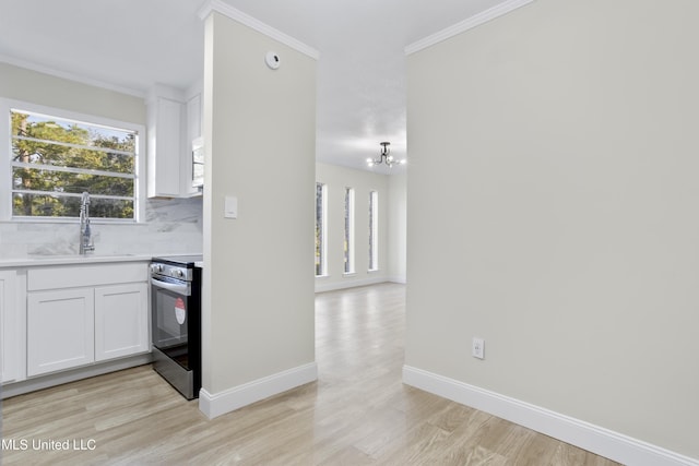 kitchen featuring electric stove, plenty of natural light, sink, and white cabinetry