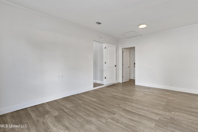 empty room with crown molding and light hardwood / wood-style floors