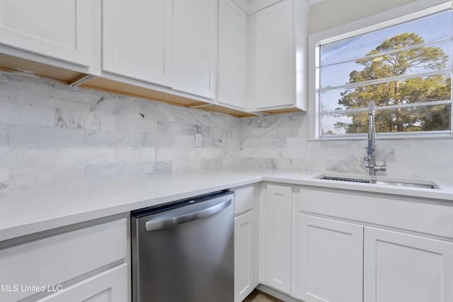 kitchen featuring stainless steel dishwasher, white cabinets, backsplash, and sink