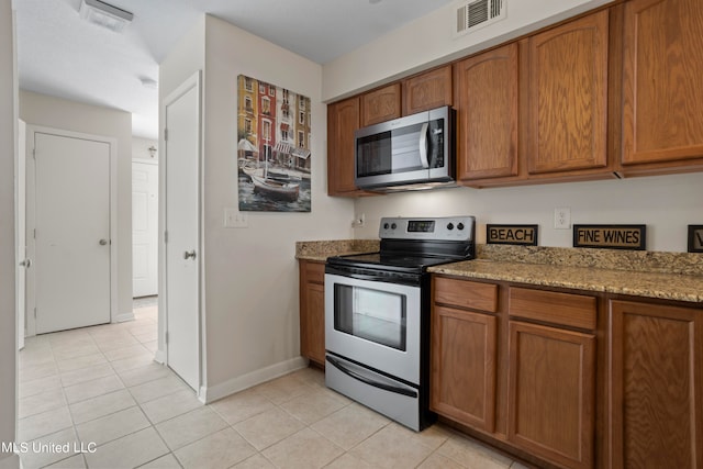 kitchen with light stone countertops, stainless steel appliances, and light tile patterned floors