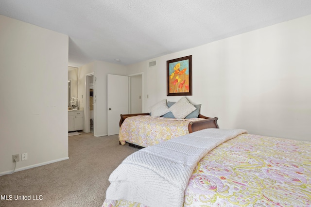 carpeted bedroom featuring ensuite bathroom and a textured ceiling