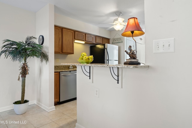 kitchen with light stone countertops, a breakfast bar, stainless steel appliances, ceiling fan, and light tile patterned floors