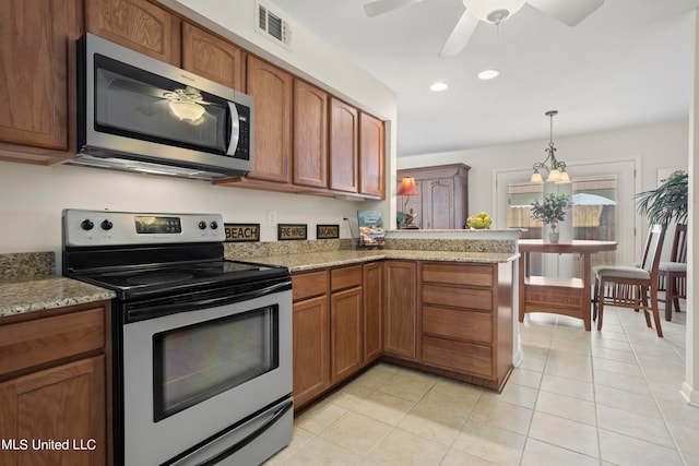 kitchen with light stone countertops, stainless steel appliances, kitchen peninsula, a chandelier, and light tile patterned flooring