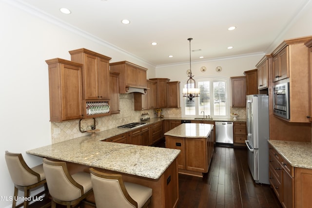 kitchen featuring dark wood-type flooring, appliances with stainless steel finishes, kitchen peninsula, pendant lighting, and light stone countertops