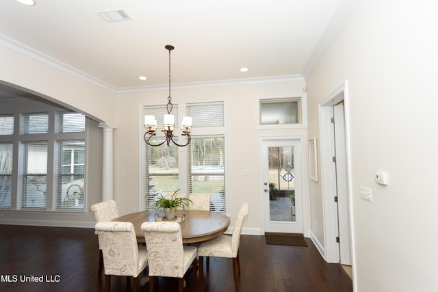 dining space with decorative columns, ornamental molding, dark wood-type flooring, and a notable chandelier