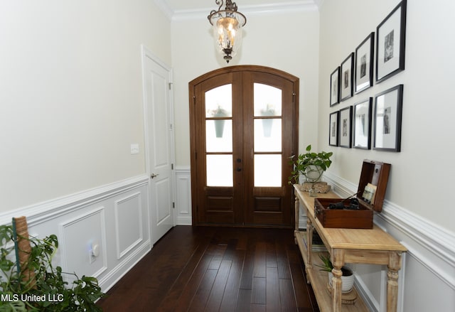 foyer entrance with crown molding, dark wood-type flooring, french doors, and a chandelier