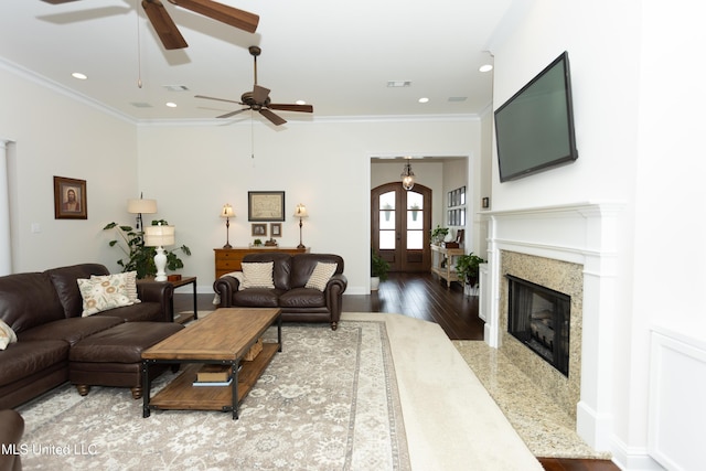 living room with a premium fireplace, ornamental molding, wood-type flooring, and french doors