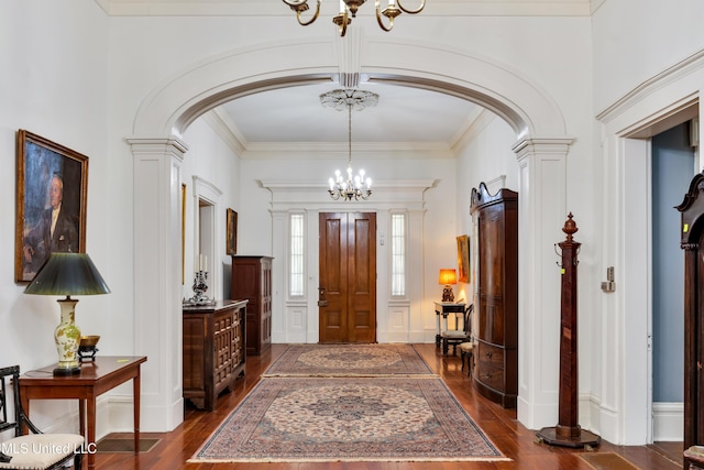 foyer entrance featuring dark hardwood / wood-style flooring, ornate columns, and crown molding