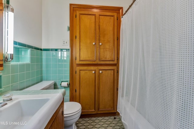 bathroom featuring toilet, tile walls, and sink