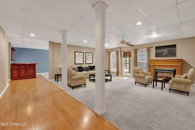 living room featuring a glass covered fireplace, decorative columns, and baseboards