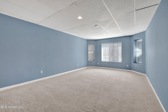 spare room featuring carpet flooring, a drop ceiling, and baseboards