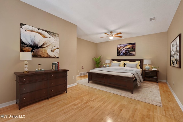 bedroom featuring baseboards, visible vents, ceiling fan, and light wood finished floors